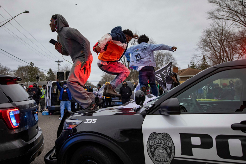 Männer springen auf die Motorhaube eines Polizeiautos, nachdem eine Familie sagte, ein Mann sei am Sonntag, dem 11. April 2021, im Brooklyn Center, Minnesota, von den Strafverfolgungsbehörden erschossen worden. (AP Photo / Christian Monterrosa)